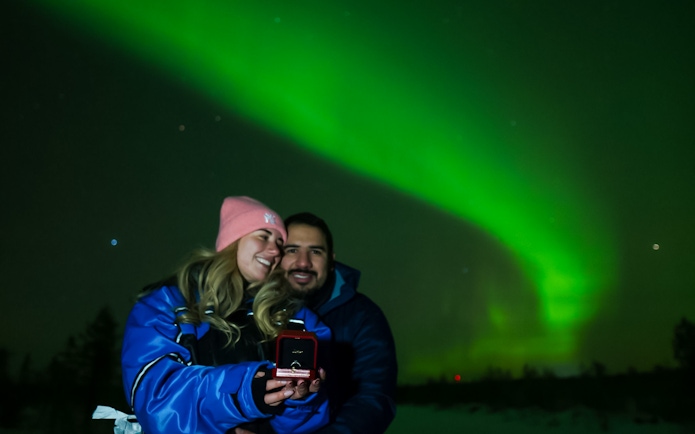 Couple enjoying Northern Lights in Rovaniemi, holding a ring box.