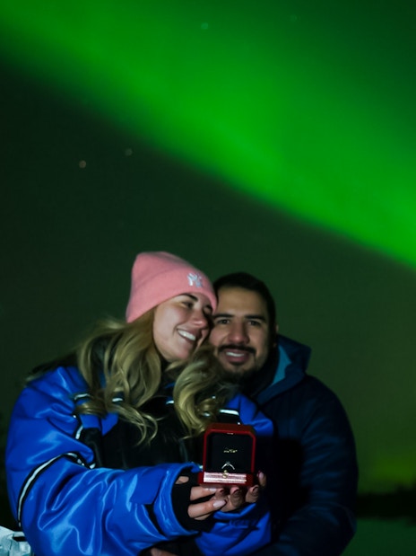 Couple enjoying Northern Lights in Rovaniemi, holding a ring box.