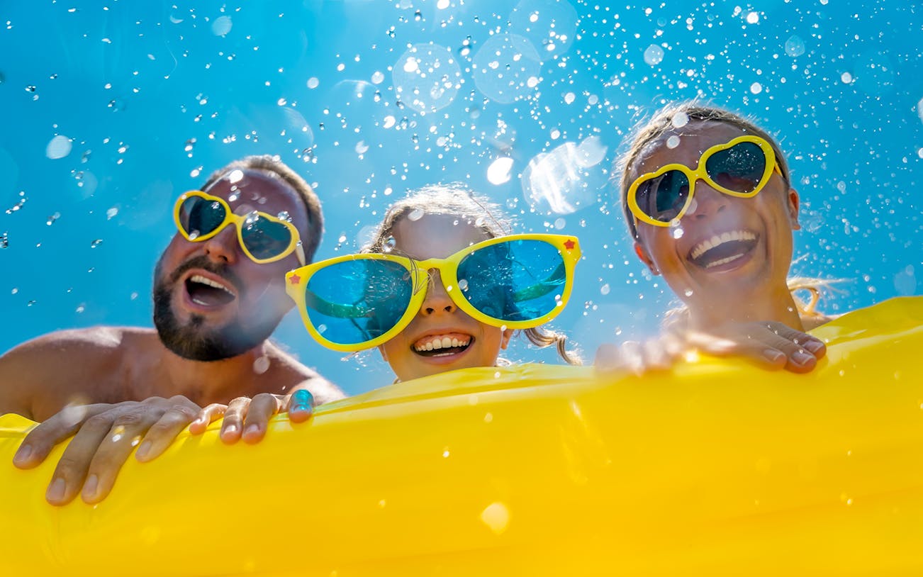 Family smiling on a yellow float at a waterpark.