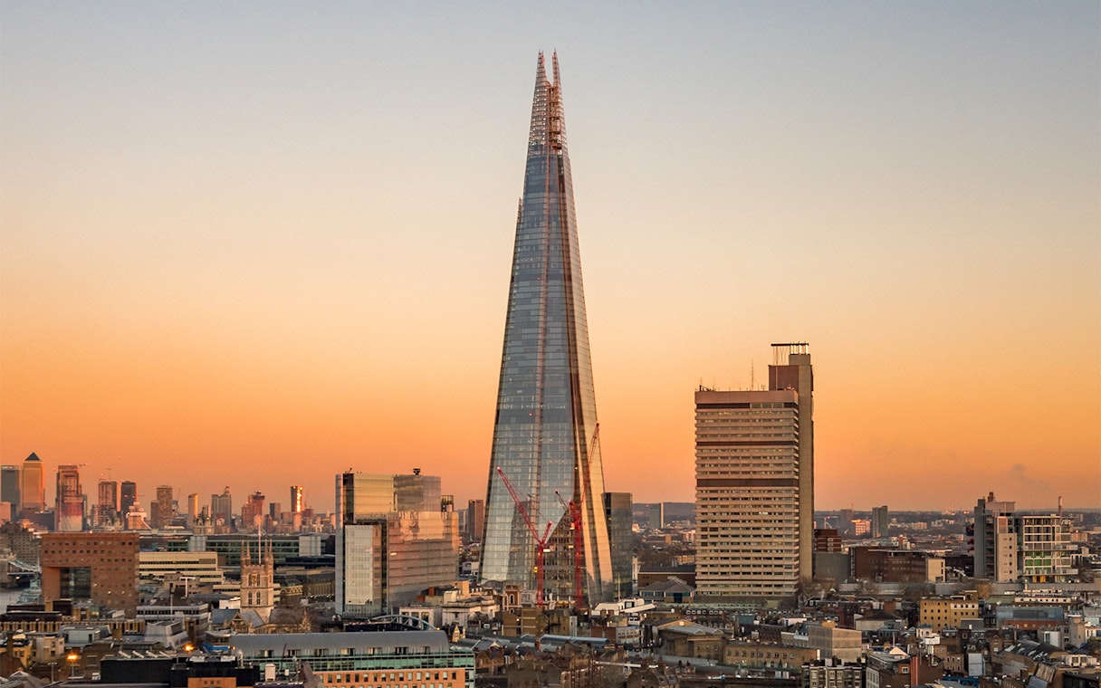 View of the Shard in London at sunset with city skyline.