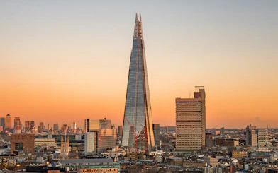 View of the Shard in London at sunset with city skyline.