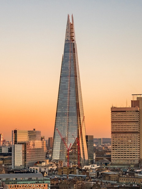 View of the Shard in London at sunset with city skyline.