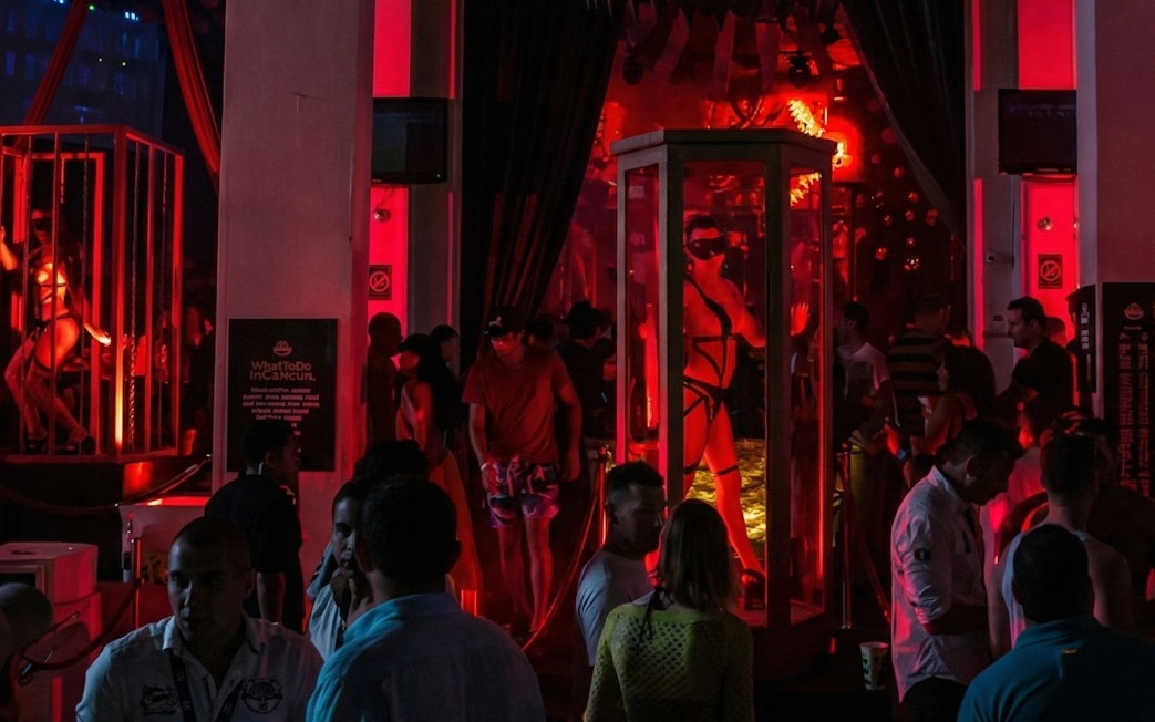 Crowded dance floor with vibrant red lighting at Mandala Nightclub Cancun.