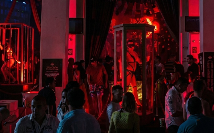Crowded dance floor with vibrant red lighting at Mandala Nightclub Cancun.