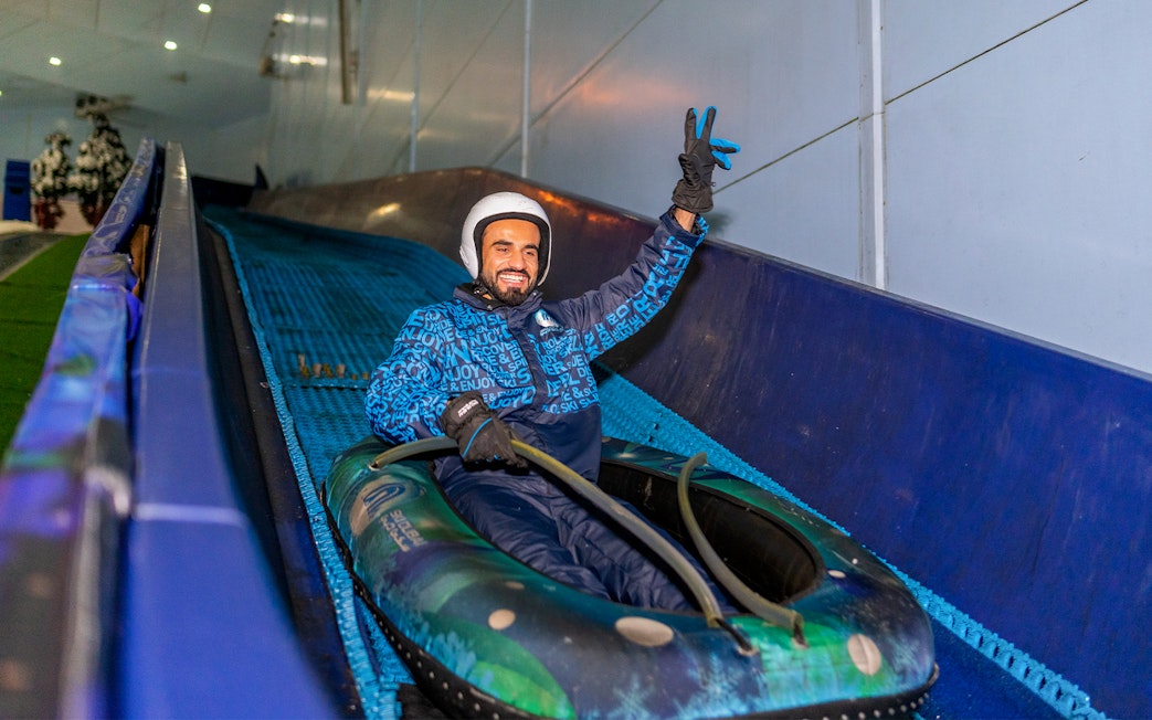 Person enjoying a snow tube ride at Ski Dubai indoor ski resort.