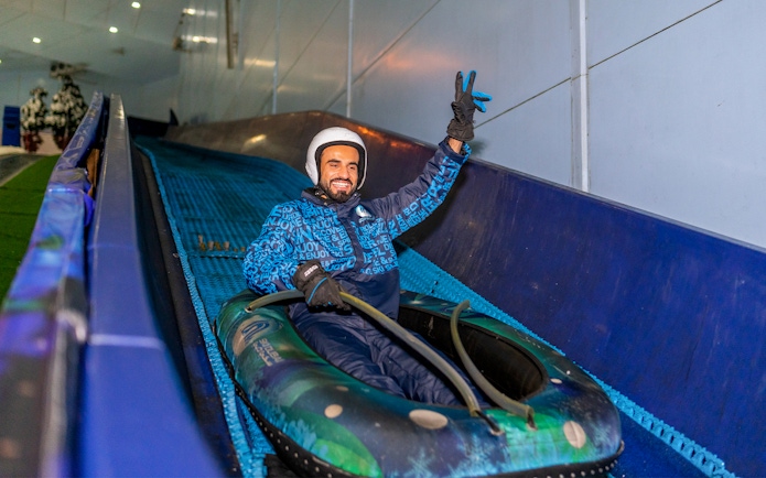 Person enjoying a snow tube ride at Ski Dubai indoor ski resort.