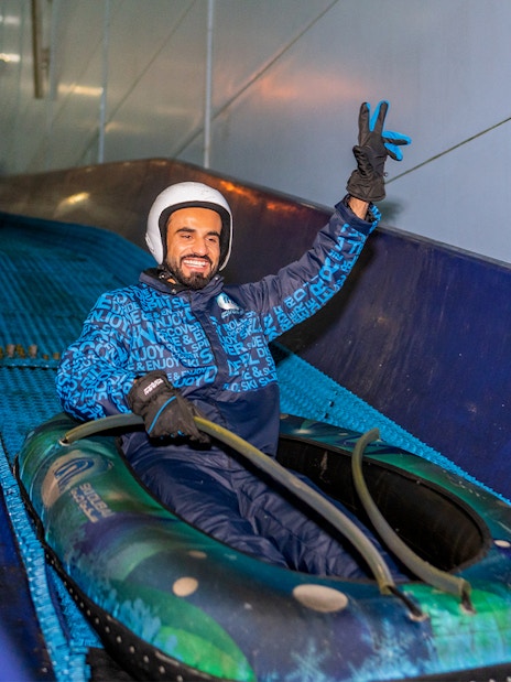 Person enjoying a snow tube ride at Ski Dubai indoor ski resort.