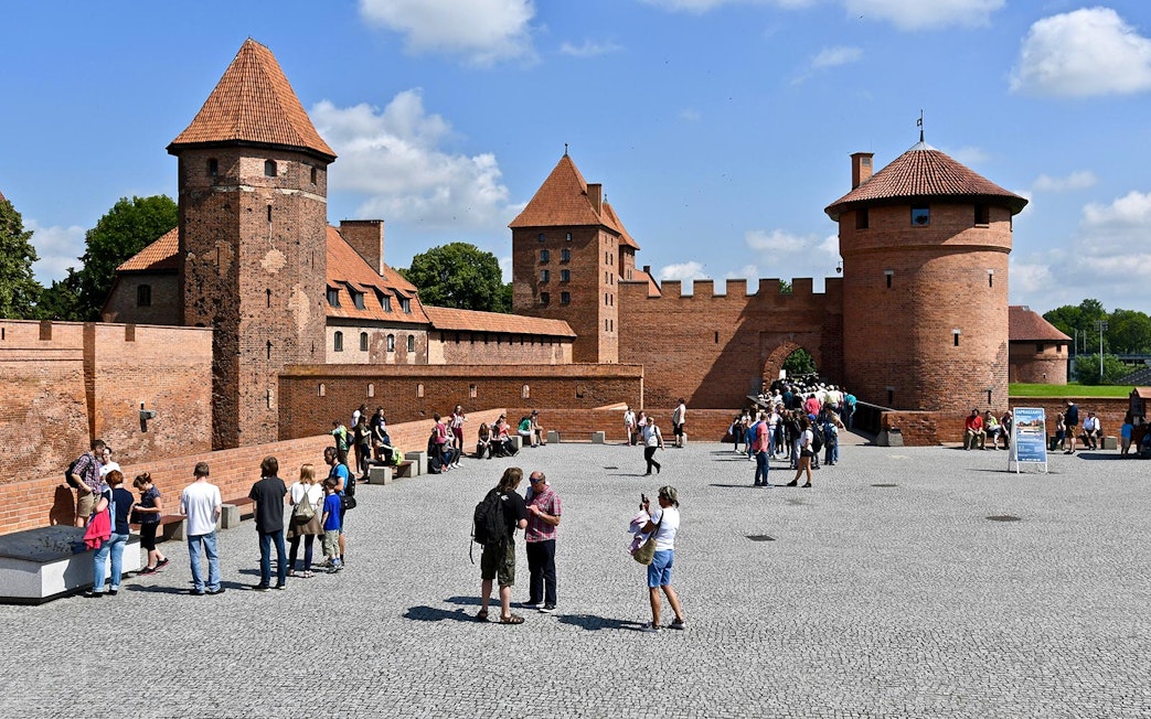 Visitors exploring Malbork Castle courtyard on a tour from Gdańsk.