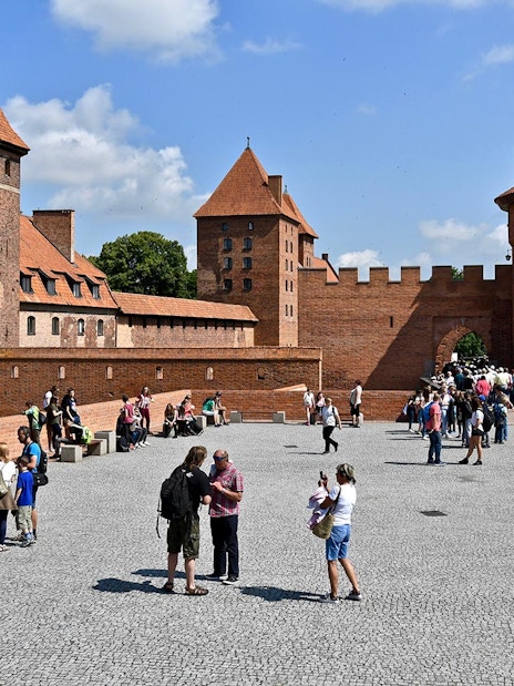 Visitors exploring Malbork Castle courtyard on a tour from Gdańsk.