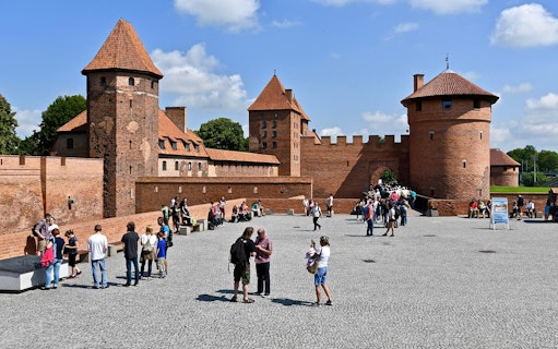 Visitors exploring the courtyard of Malbork Castle during an audio guide tour from Gdańsk.