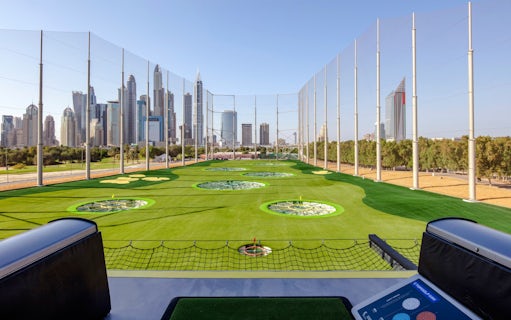 Driving range at Topgolf Dubai with city skyline in the background.