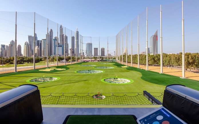 Driving range at Topgolf Dubai with city skyline in the background.