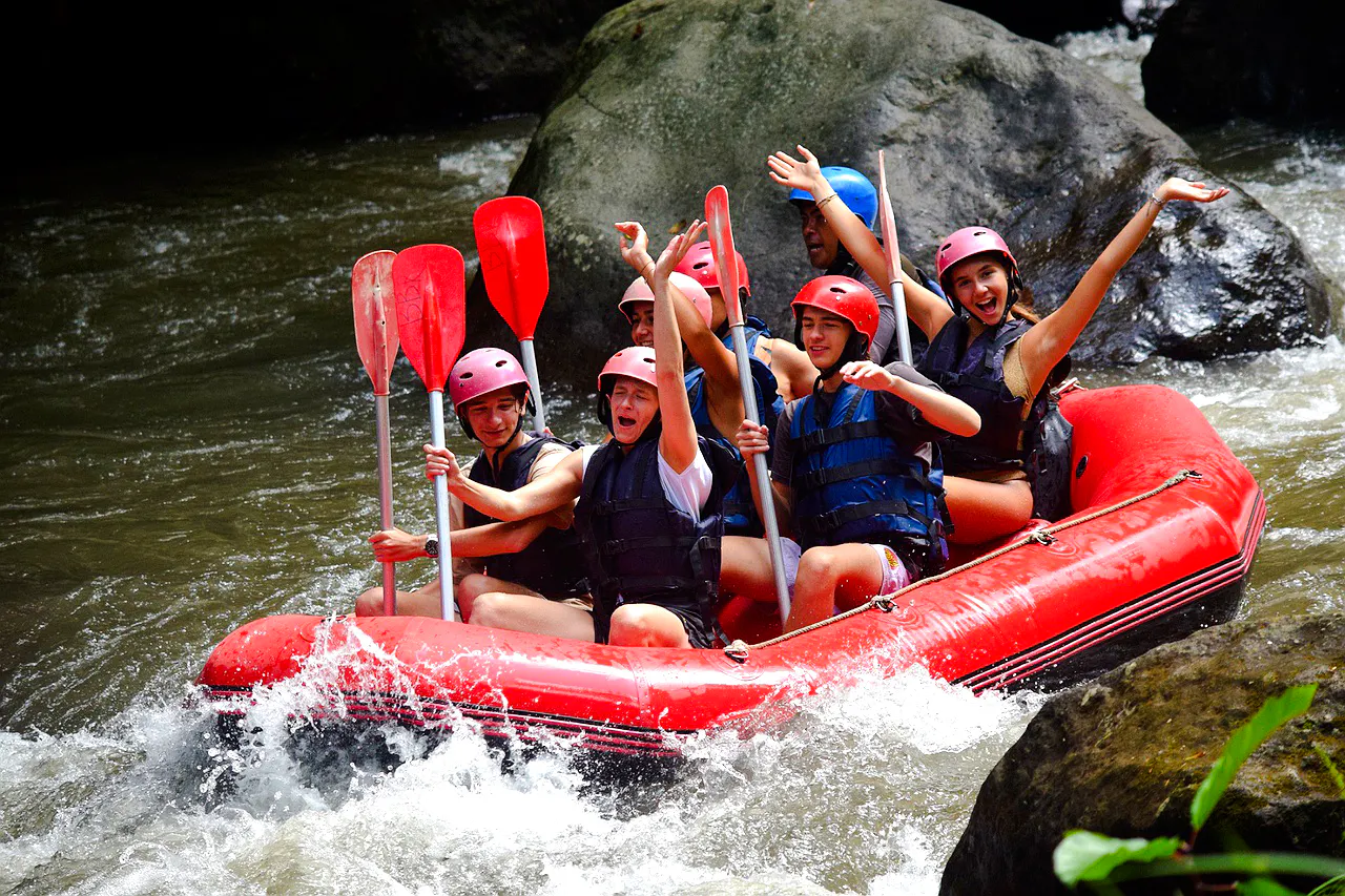 Group rafting on Ayung River, Bali, navigating rapids in a red inflatable raft.
