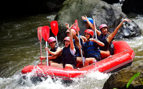 Group rafting on Ayung River, Bali, navigating rapids in a red inflatable raft.