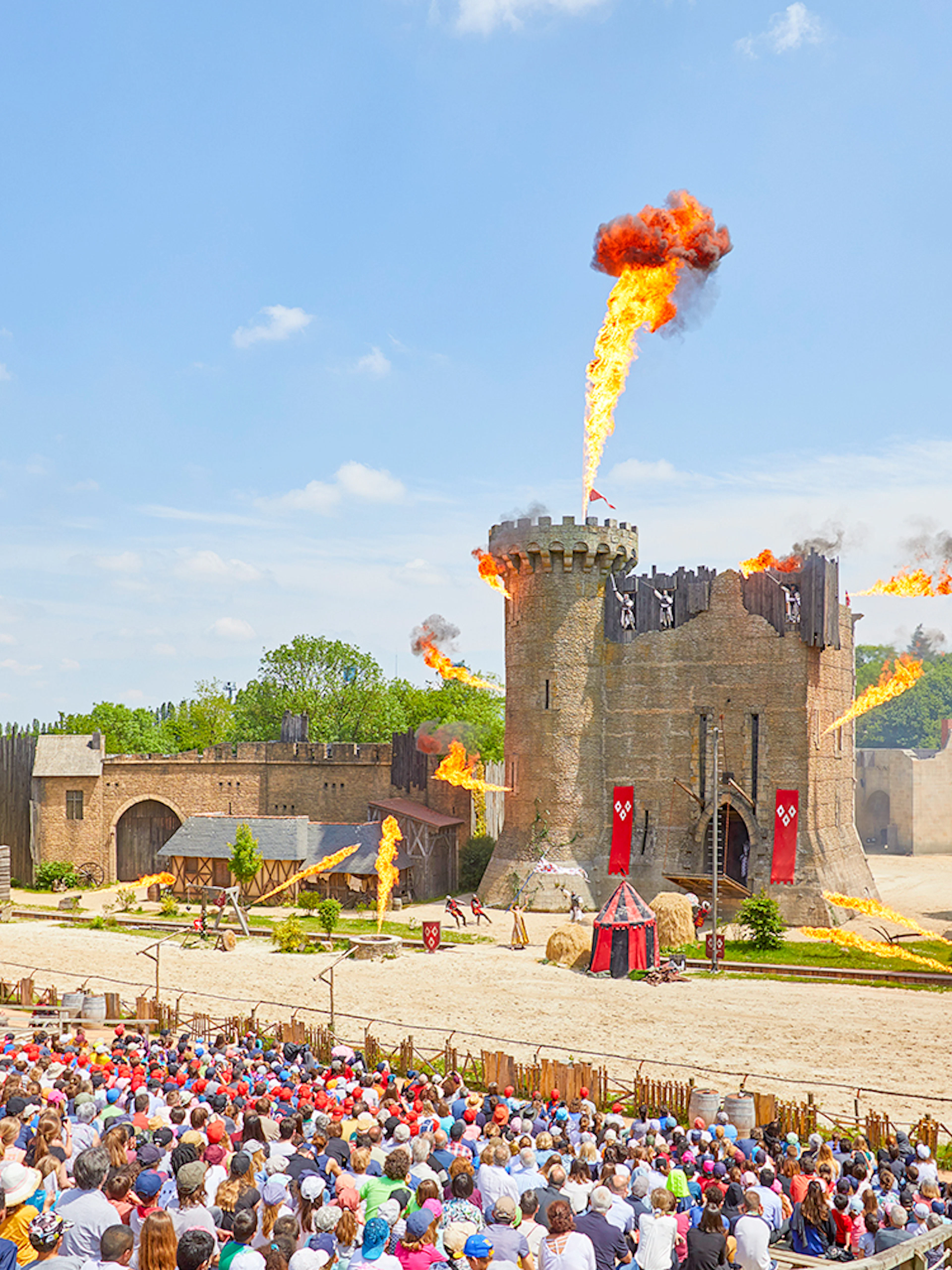Crowd watching medieval castle show with fire effects at Puy du Fou, France.