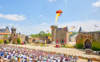 Crowd watching medieval castle show with fire effects at Puy du Fou, France.
