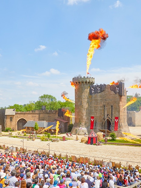 Crowd watching medieval castle show with fire effects at Puy du Fou, France.