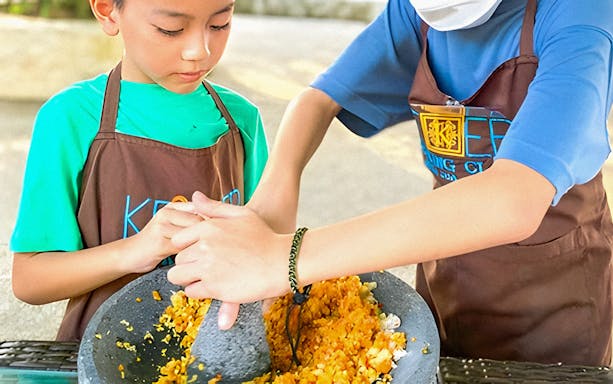 Children learning to grind spices at Kekeb Balinese Cooking Class in Nusa Dua.