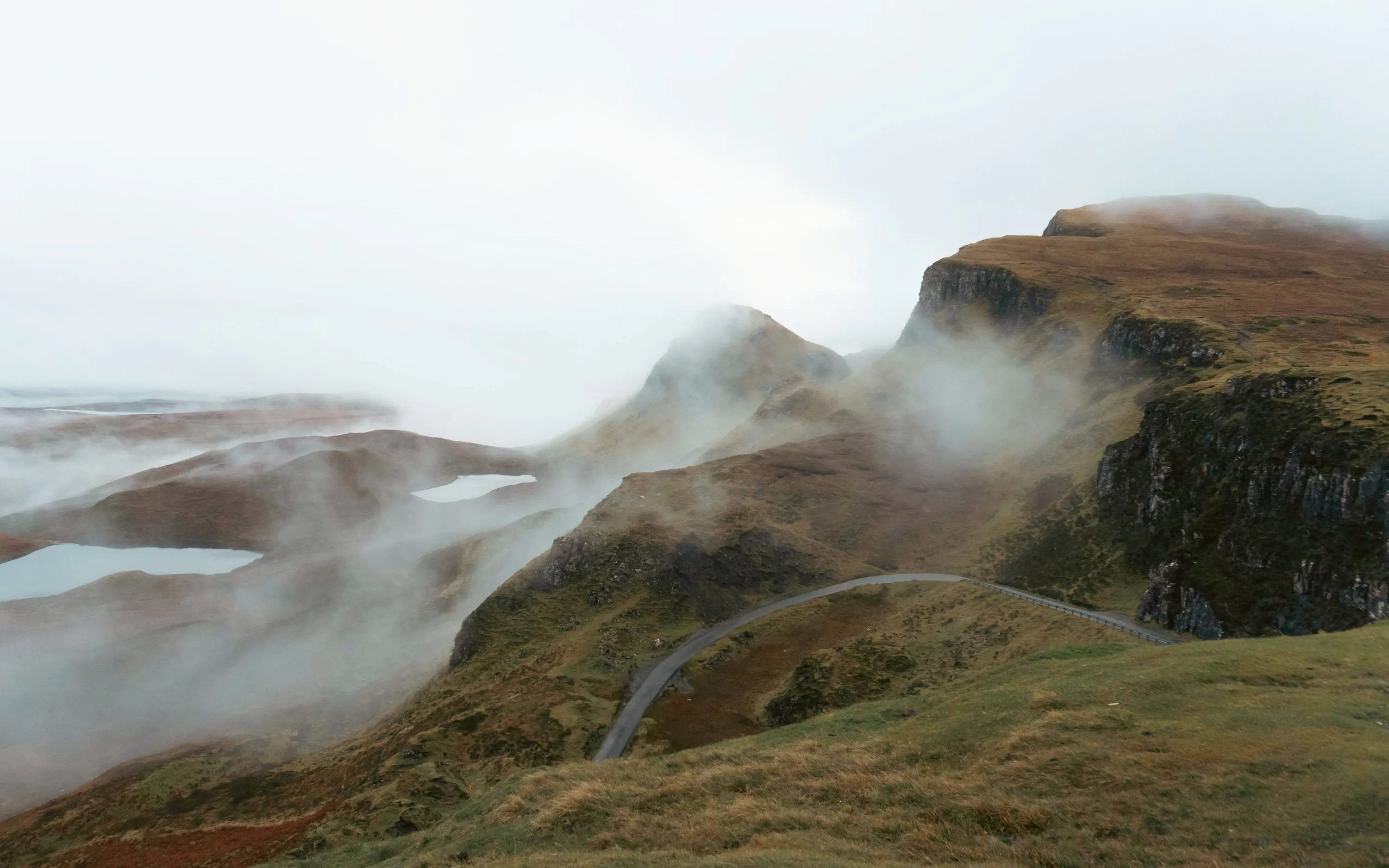 Moody landscape of Quiraing with misty hills and winding road, Isle of Skye, Scotland.