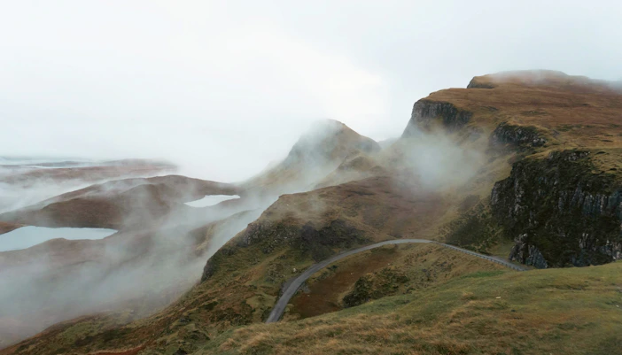 Moody landscape of Quiraing with misty hills and winding road, Isle of Skye, Scotland.