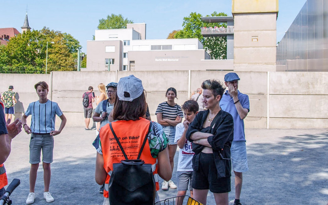 Group of tourists listening to a guide during a Berlin Wall bike tour.