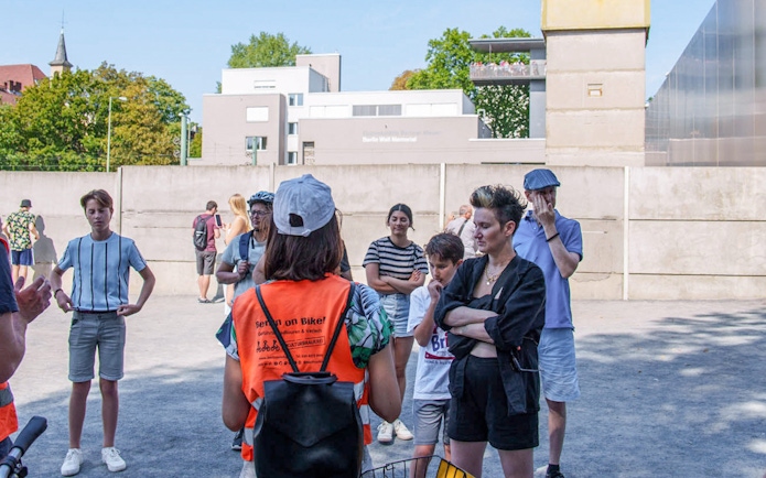 Group of tourists listening to a guide during a Berlin Wall bike tour.