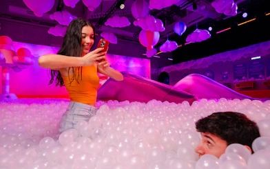 Person taking a photo in a colorful ball pit at Bubble Planet, Cologne.