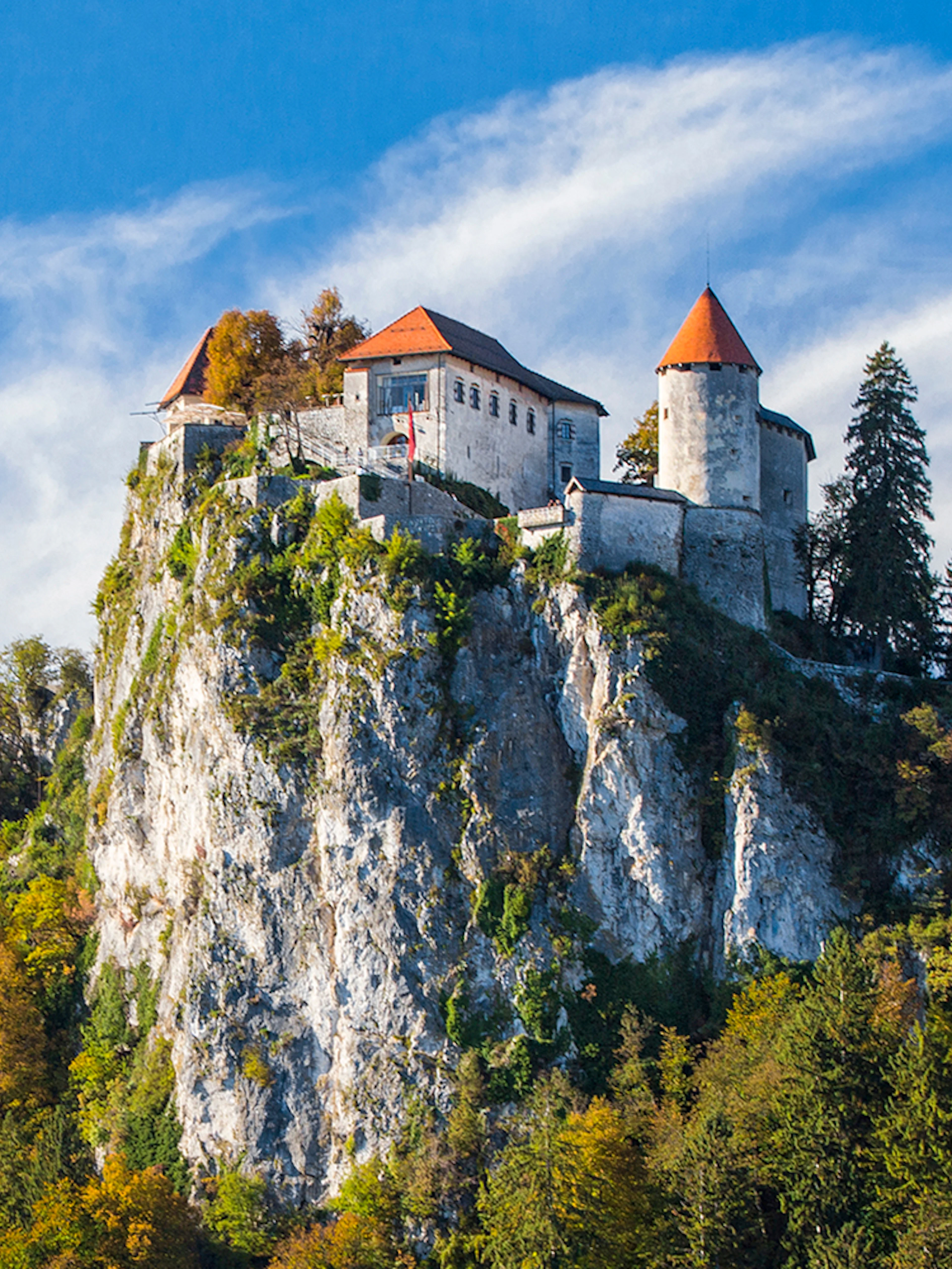 Bled Castle perched on a cliff surrounded by autumn trees, Slovenia.