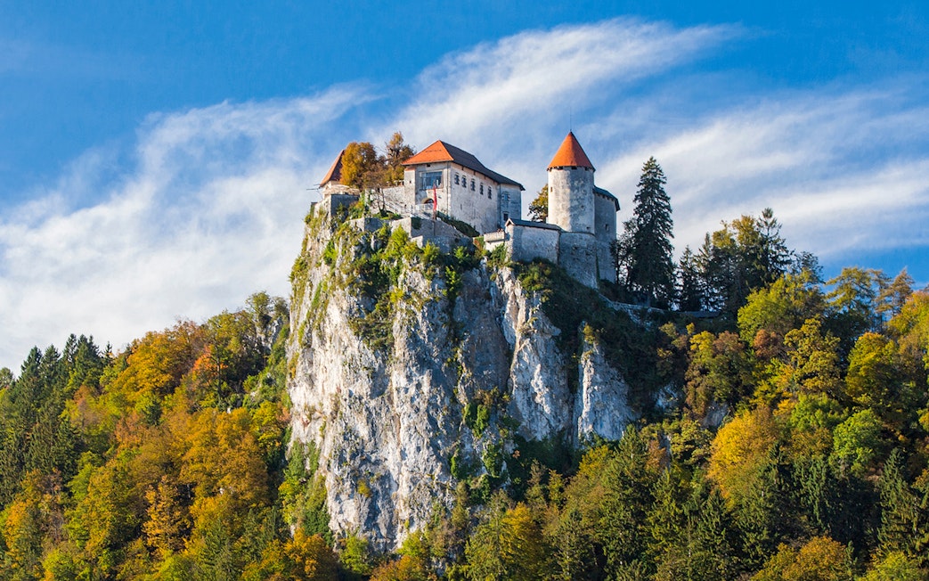 Bled Castle perched on a cliff surrounded by autumn trees, Slovenia.