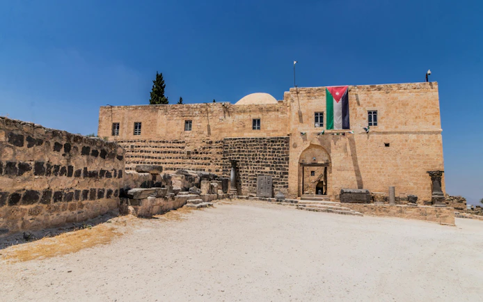 Umm Qays Museum with Jordanian flag, ancient stone walls, Umm Qais, Jordan.