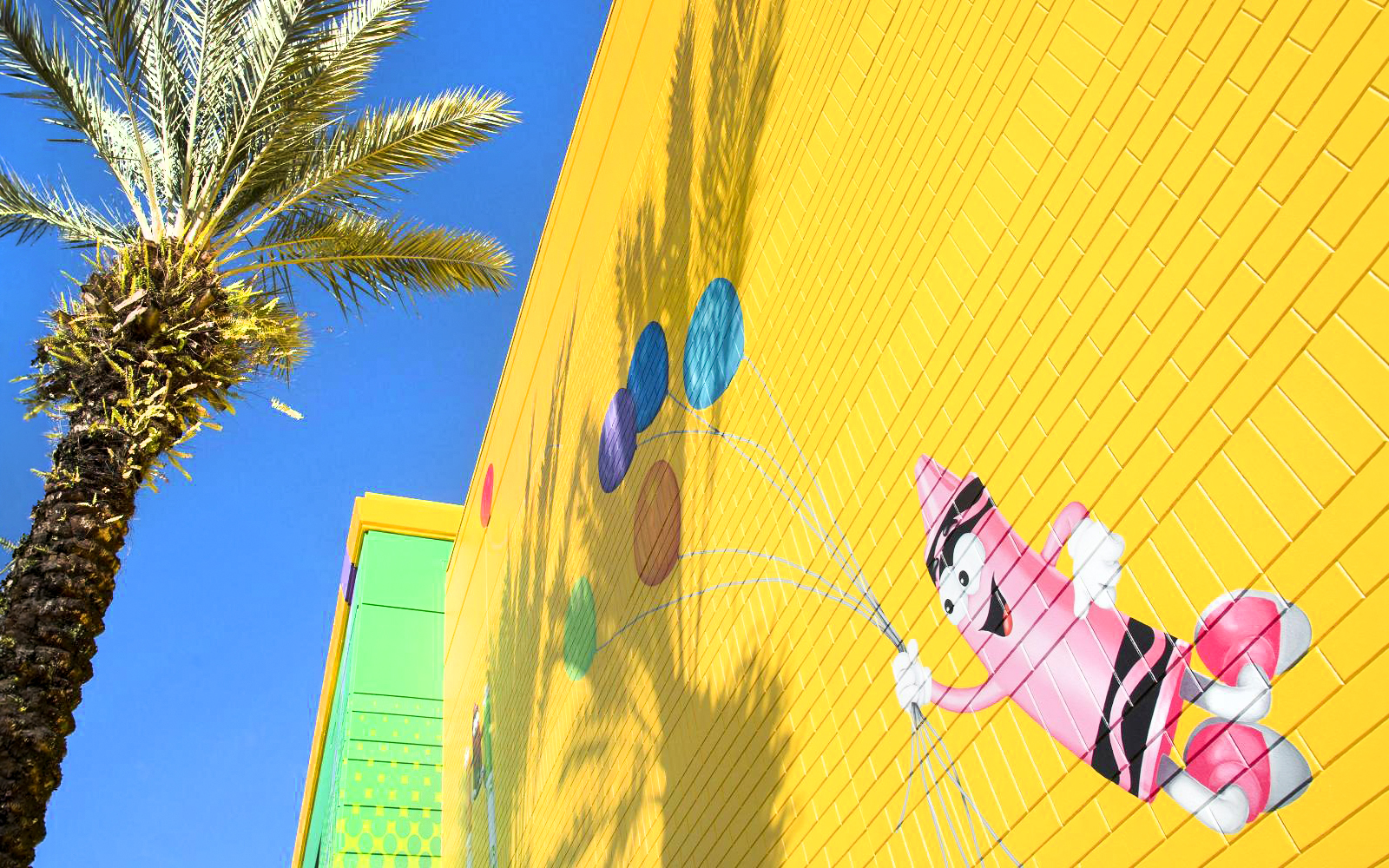 Crayola Experience Orlando mural with colorful crayon character and palm tree.