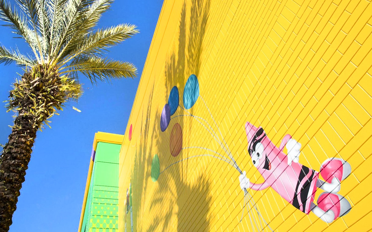 Crayola Experience Orlando mural with colorful crayon character and palm tree.