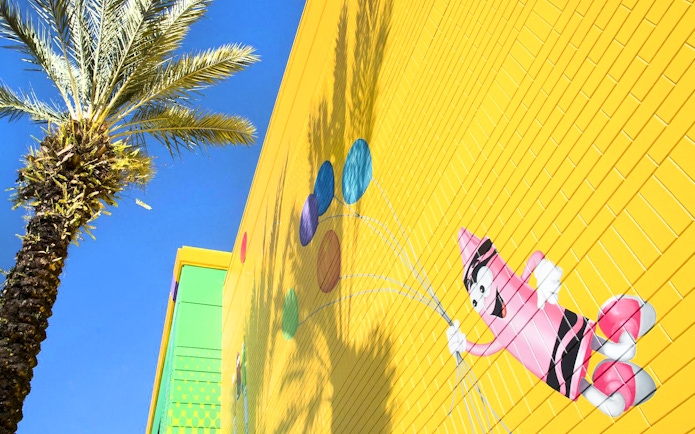 Crayola Experience Orlando mural with colorful crayon character and palm tree.