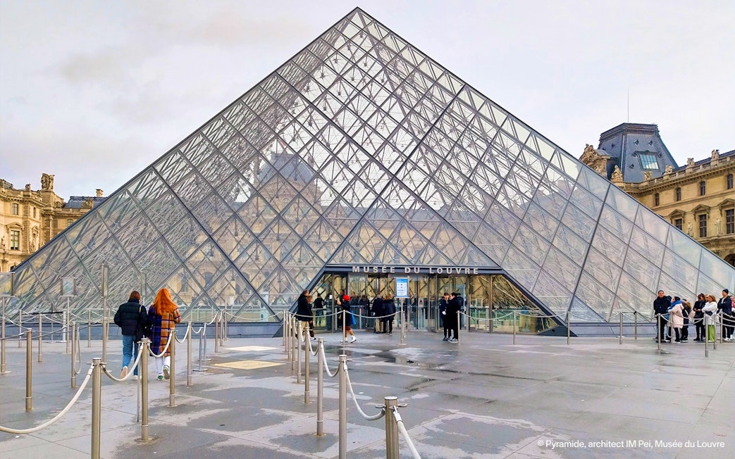 Louvre Pyramid entrance with visitors in Paris, France.