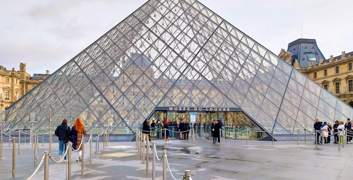 Louvre Pyramid entrance with visitors in Paris, France.