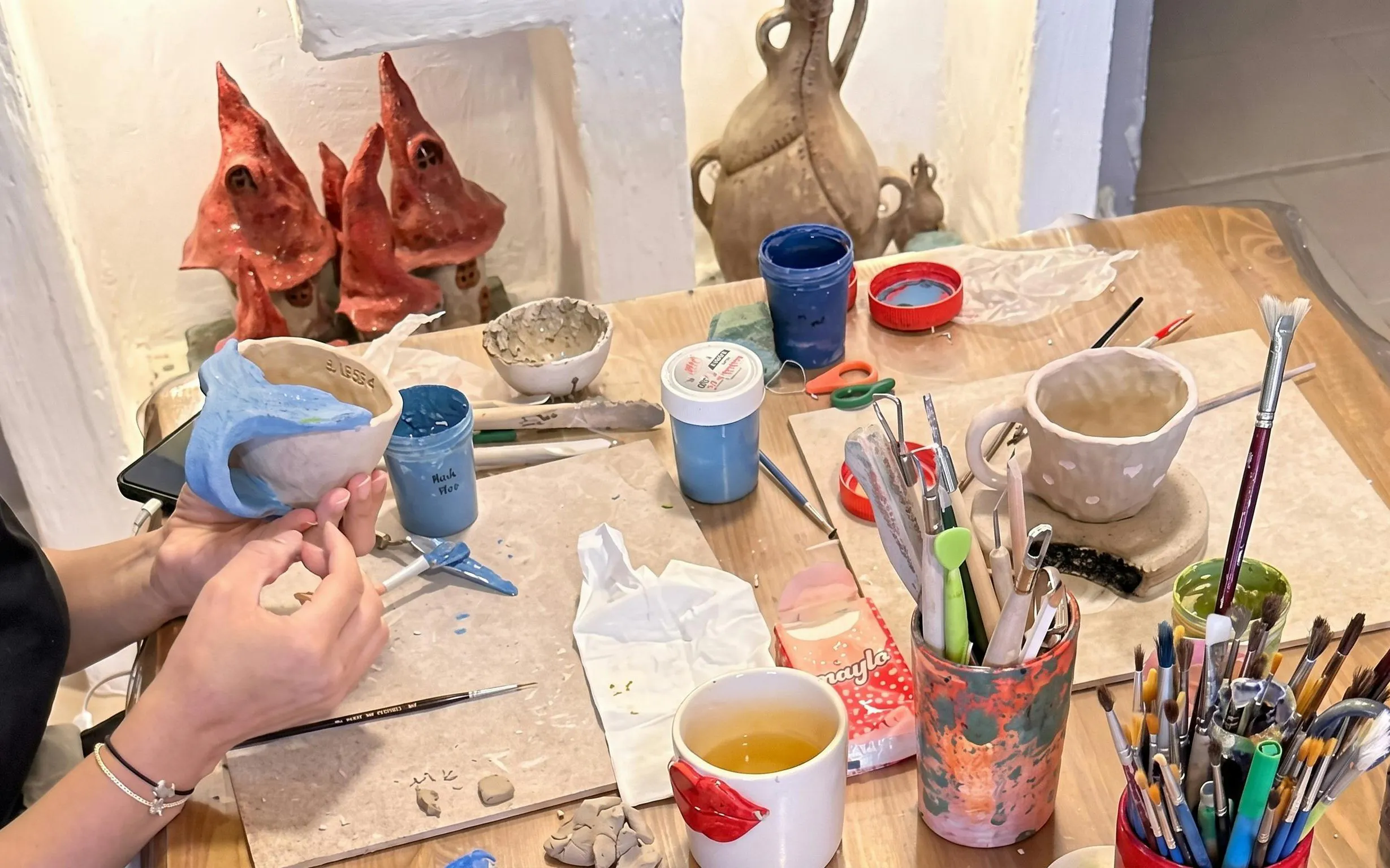 Visitor painting a blue design on a coffee mug during pottery workshop in Bouchane.