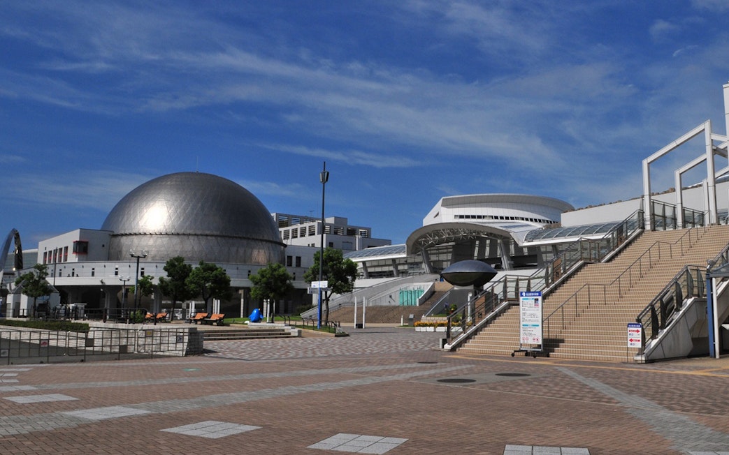 Port of Nagoya Public Aquarium entrance with dome and stairs under blue sky.