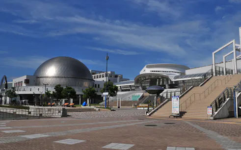 Port of Nagoya Public Aquarium entrance with dome and stairs under blue sky.