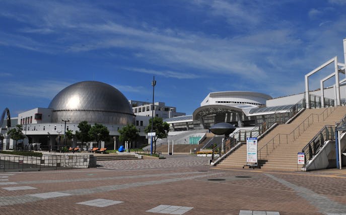 Port of Nagoya Public Aquarium entrance with dome and stairs under blue sky.