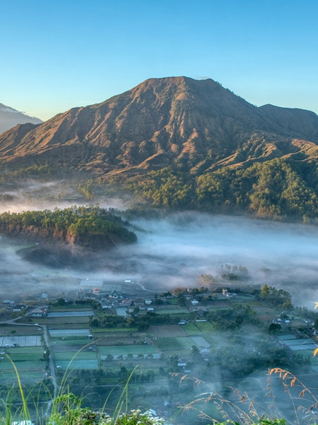 Mount Batur with morning mist and surrounding landscape in Bali, Indonesia.