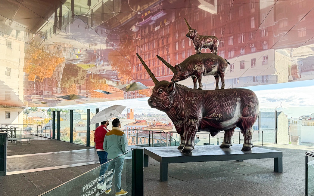 Visitors viewing a stacked animal sculpture at Reina Sofia Museum, Madrid.