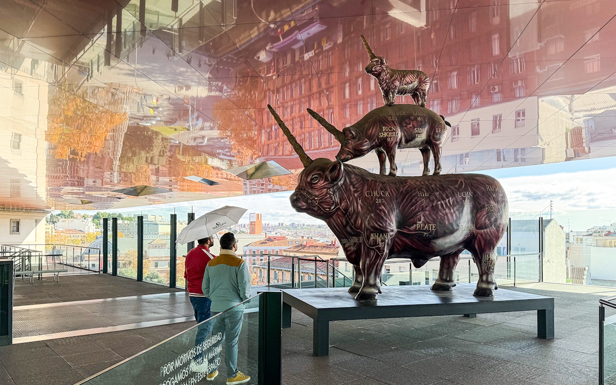 Visitors viewing a stacked animal sculpture at Reina Sofia Museum, Madrid.