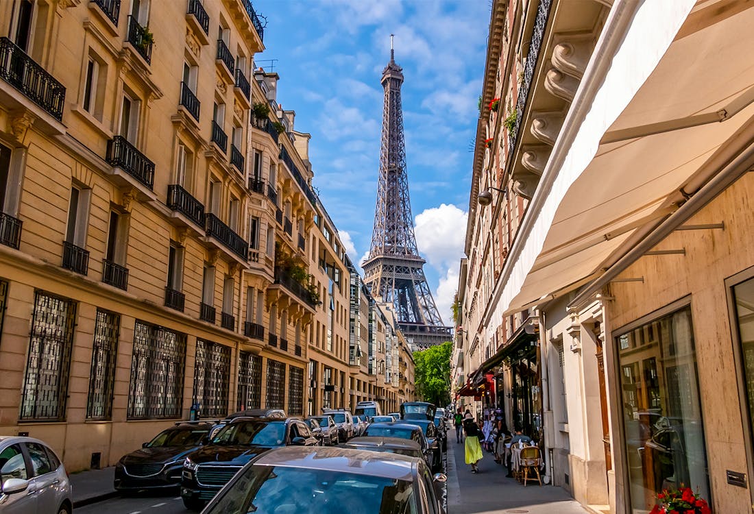 Narrow Paris street with view of Eiffel Tower in the background.