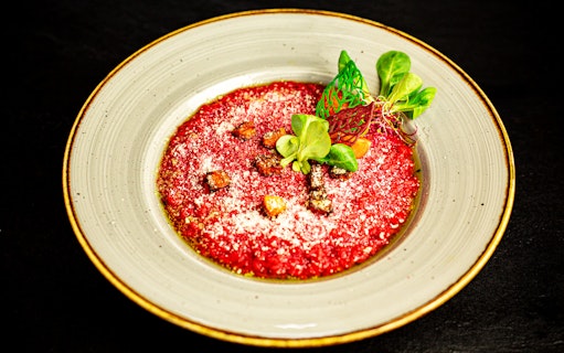 Beetroot risotto garnished with greens, part of a 7-course dinner cruise on the Danube River.