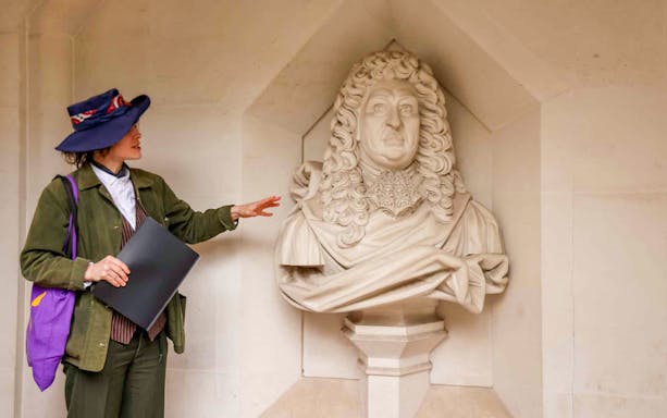 Tour guide explaining a historical statue in London during the Heart of 'The City' Food Tour.