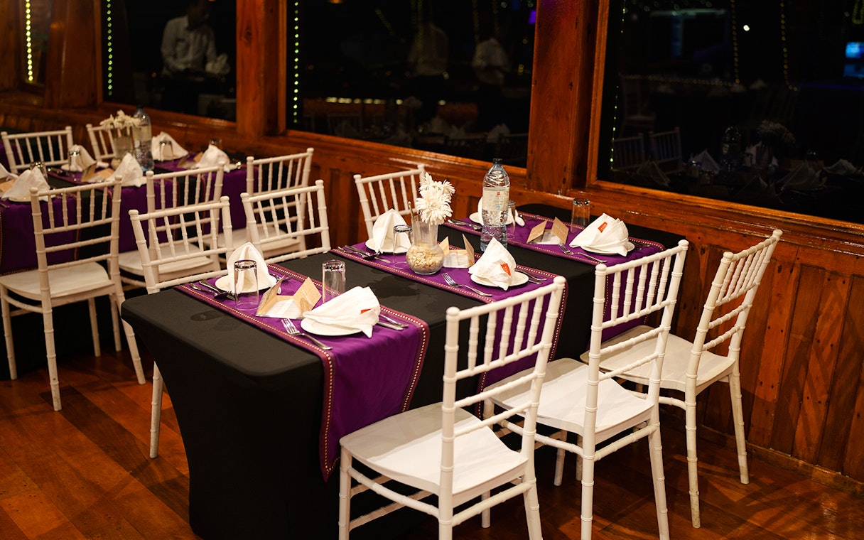 Dining setup on Dubai Marina dhow cruise with tables set for 5-star Indian dinner.