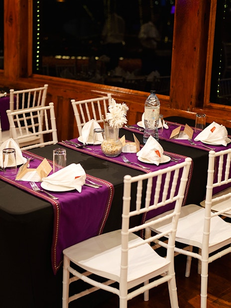 Dining setup on Dubai Marina dhow cruise with tables set for 5-star Indian dinner.