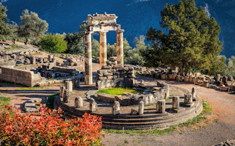 Tholos of Delphi ruins surrounded by trees at Delphi Archaeological Site, Greece.