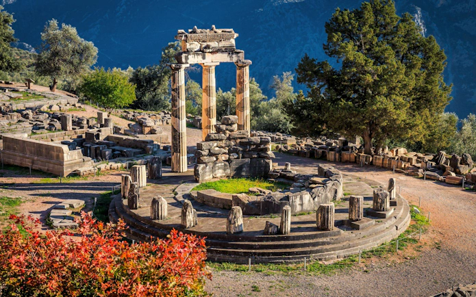 Tholos of Delphi ruins surrounded by trees at Delphi Archaeological Site, Greece.