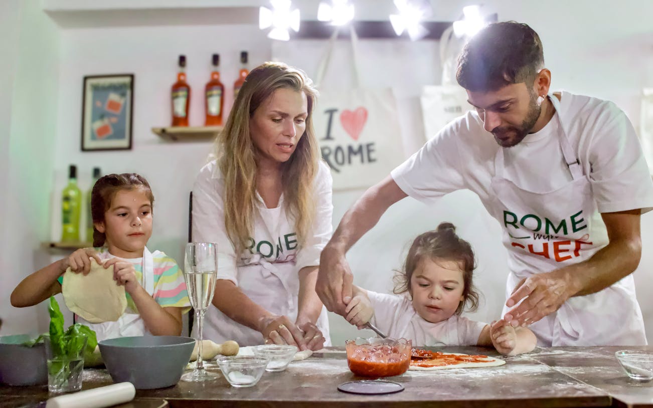 Family making pizza during a cooking class in Rome.
